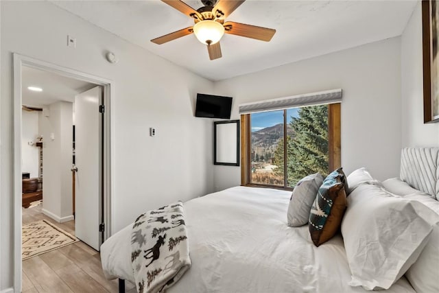 bedroom with light wood-style floors, baseboards, and ceiling fan