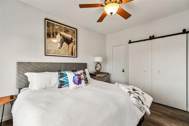 bedroom featuring a barn door, wood finished floors, and ceiling fan