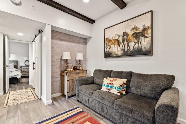 living room featuring a barn door, light wood-style flooring, baseboards, beam ceiling, and recessed lighting