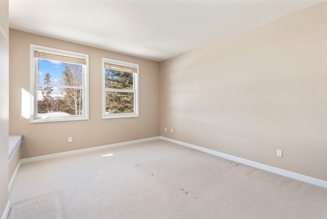 spare room with light colored carpet and baseboards