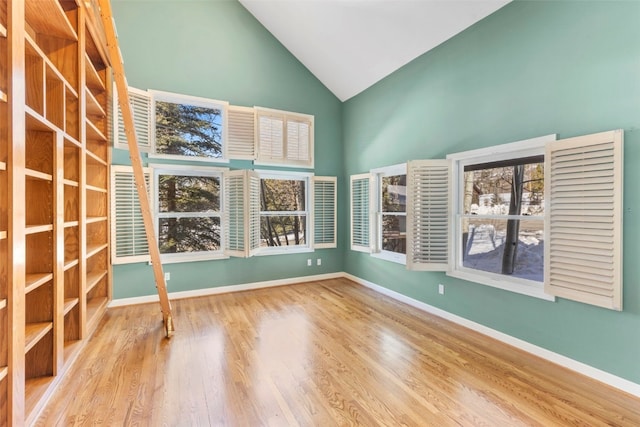 unfurnished room with baseboards, high vaulted ceiling, and wood finished floors