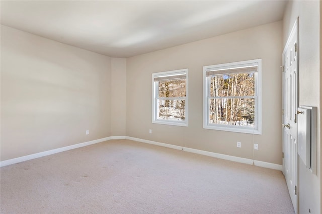 unfurnished room with light colored carpet and baseboards