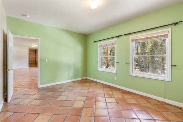 spare room with light tile patterned flooring and baseboards