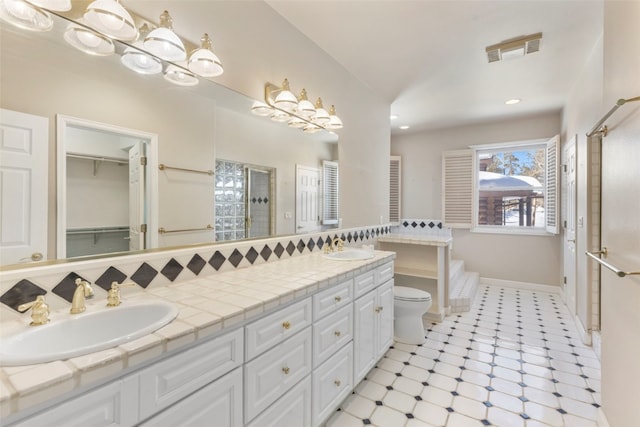 bathroom featuring visible vents, a sink, a shower stall, and double vanity