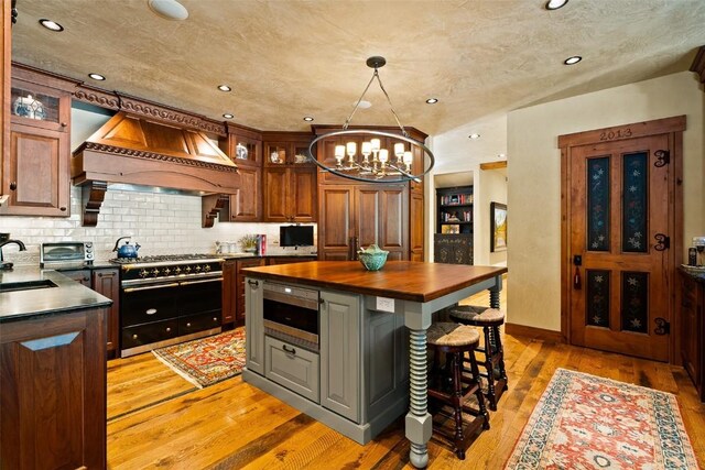 197 Wild Irishman Rd, Keystone, CO 80435 - kitchen with custom exhaust hood, double oven range, wooden counters, stainless steel microwave, and a sink