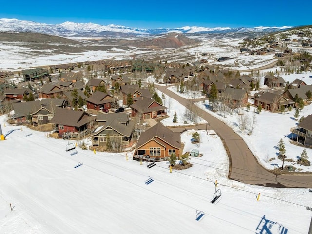 snowy aerial view with a mountain view and a residential view