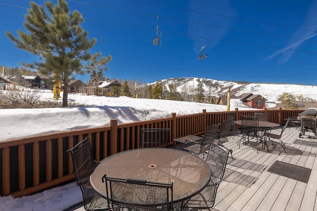 snow covered deck with outdoor dining area and a mountain view
