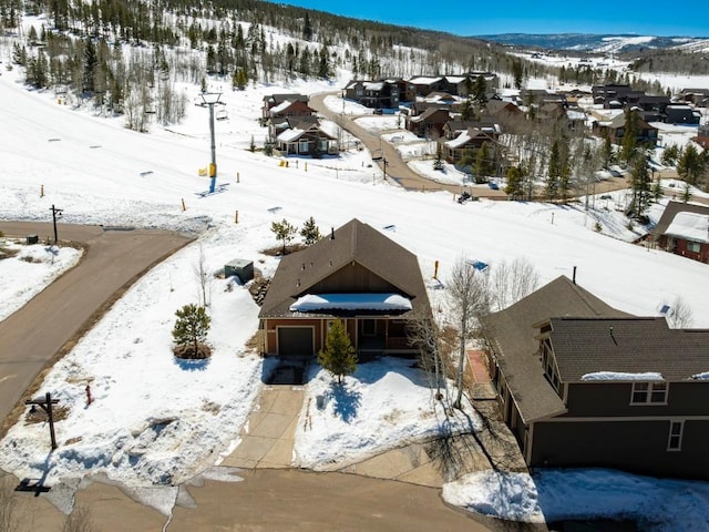 snowy aerial view featuring a residential view and a mountain view