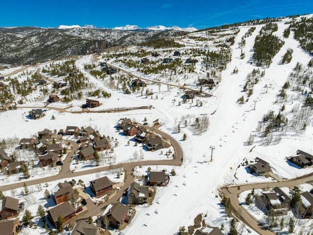 snowy aerial view with a mountain view and a residential view