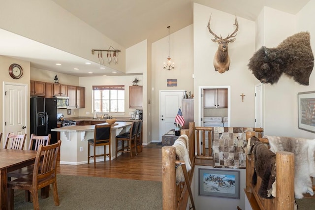 living area featuring high vaulted ceiling, dark carpet, a notable chandelier, dark wood-type flooring, and recessed lighting