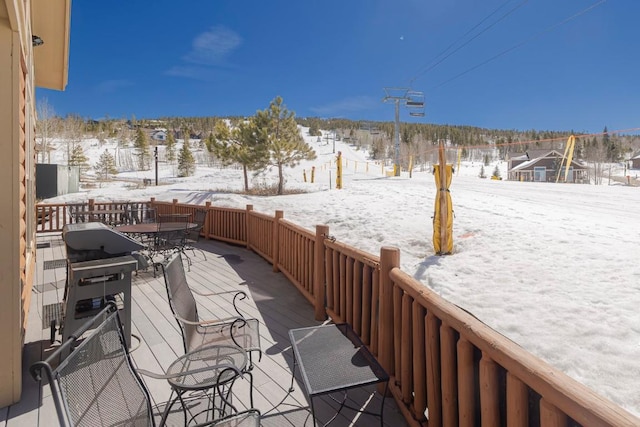 snow covered patio with a wooden deck and outdoor dining area