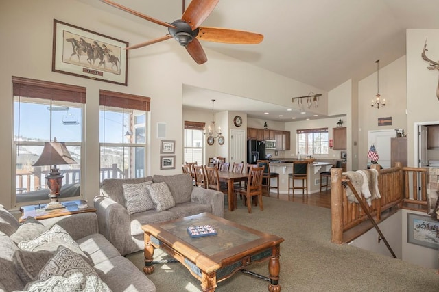 living area featuring ceiling fan with notable chandelier and high vaulted ceiling
