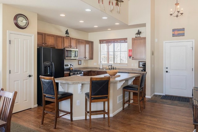 kitchen featuring light countertops, a kitchen bar, appliances with stainless steel finishes, dark wood-type flooring, and recessed lighting
