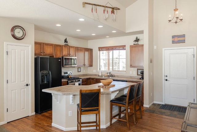 kitchen with brown cabinets, appliances with stainless steel finishes, dark wood-type flooring, and a breakfast bar