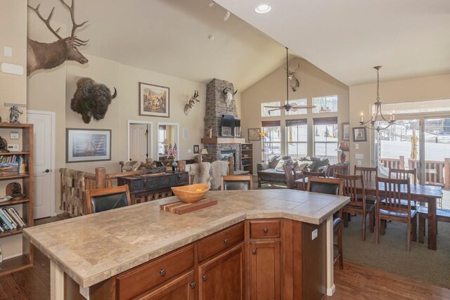 kitchen featuring dark wood finished floors, a stone fireplace, a ceiling fan, tile countertops, and open floor plan