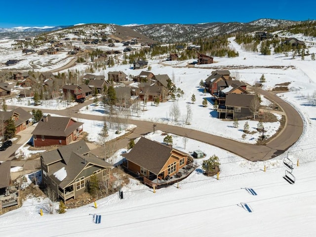 snowy aerial view featuring a mountain view and a residential view