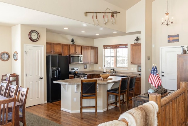 kitchen featuring brown cabinets, a breakfast bar area, stainless steel appliances, light countertops, and a kitchen island