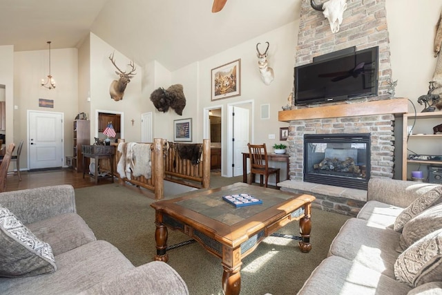 carpeted living area with a fireplace, visible vents, high vaulted ceiling, and a notable chandelier