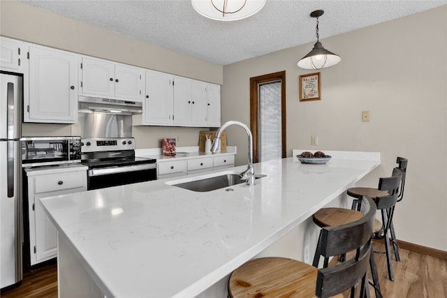 24 Ski Pole Ct, Breckenridge, CO 80424 - kitchen with appliances with stainless steel finishes, under cabinet range hood, dark wood finished floors, white cabinetry, and a textured ceiling