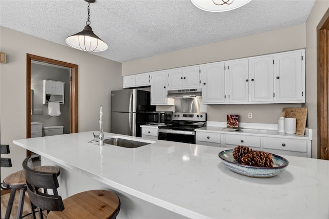 24 Ski Pole Ct, Breckenridge, CO 80424 - kitchen featuring stainless steel appliances, under cabinet range hood, a textured ceiling, white cabinetry, and a breakfast bar