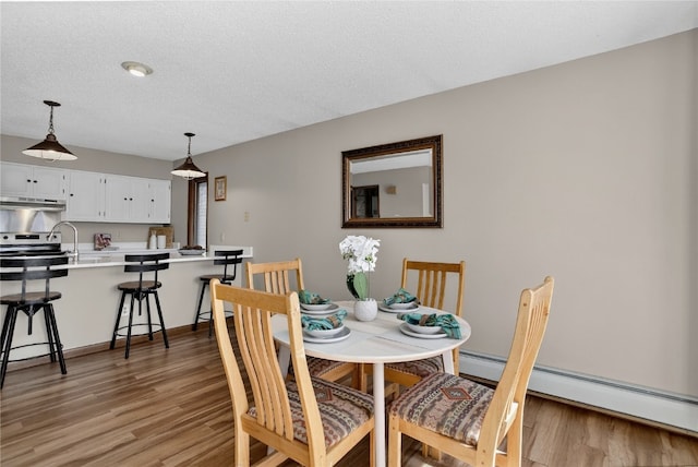 24 Ski Pole Ct, Breckenridge, CO 80424 - dining area featuring a baseboard heating unit, light wood-style floors, and a textured ceiling