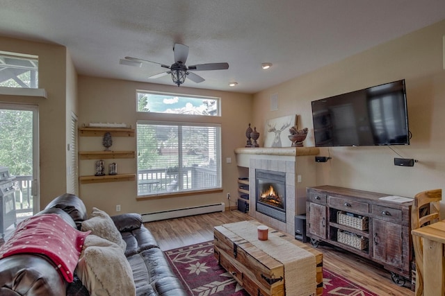 102 Creek Ln Unit 102, Silverthorne, CO 80498 - living room with a baseboard radiator, wood finished floors, a tile fireplace, and ceiling fan