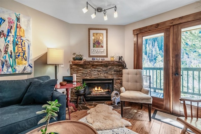 sitting room with plenty of natural light, hardwood / wood-style flooring, and a stone fireplace