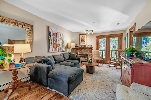 living area featuring wood finished floors, a healthy amount of sunlight, and a stone fireplace