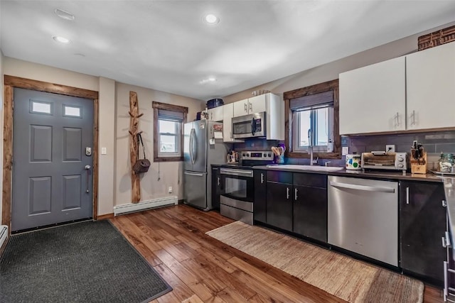 kitchen featuring a baseboard radiator, a wealth of natural light, stainless steel appliances, and a sink