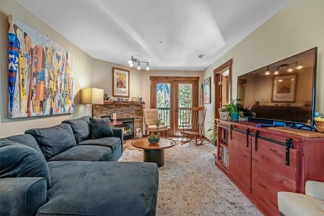 living area featuring light colored carpet, rail lighting, and a stone fireplace