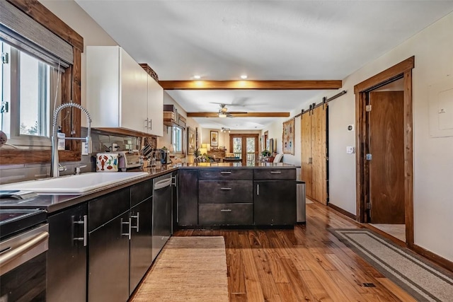 kitchen with wood finished floors, a sink, dishwasher, white cabinets, and a peninsula