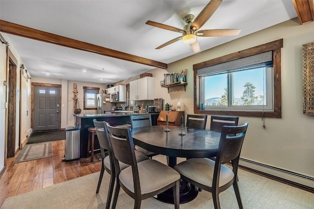 dining area with a baseboard heating unit, light wood-style floors, beam ceiling, and a wealth of natural light