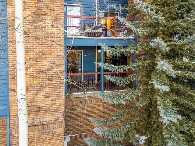 exterior space featuring a balcony and brick siding