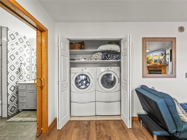 washroom featuring washing machine and dryer, wood finished floors, baseboards, and laundry area