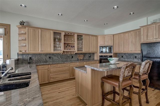 1235 Elk Run Rd, Silverthorne, CO 80498 - kitchen with black appliances, open shelves, light brown cabinets, a sink, and a kitchen breakfast bar
