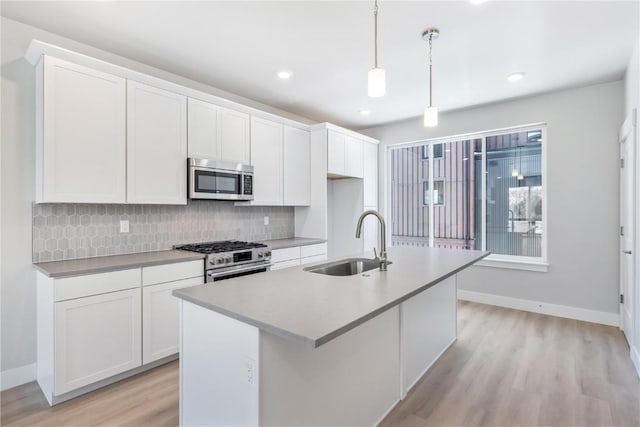 kitchen with pendant lighting, white cabinets, a center island with sink, sink, and stainless steel appliances