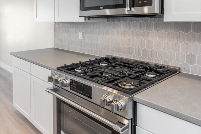 kitchen with white cabinetry, light hardwood / wood-style flooring, high end stainless steel range, and tasteful backsplash