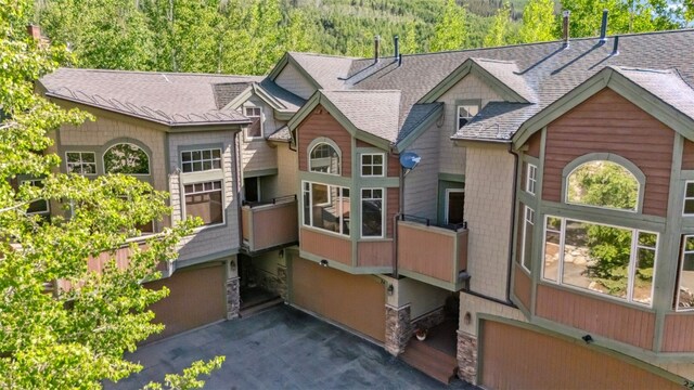 24 Rasor Dr Unit 24, Keystone, CO 80435 - view of front of house featuring an attached garage, asphalt driveway, a shingled roof, stone siding, and a view of trees