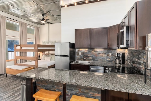 22174 US Highway 6 Unit 7, Keystone, CO 80435 - kitchen with appliances with stainless steel finishes, dark brown cabinets, tasteful backsplash, a kitchen bar, and a ceiling fan