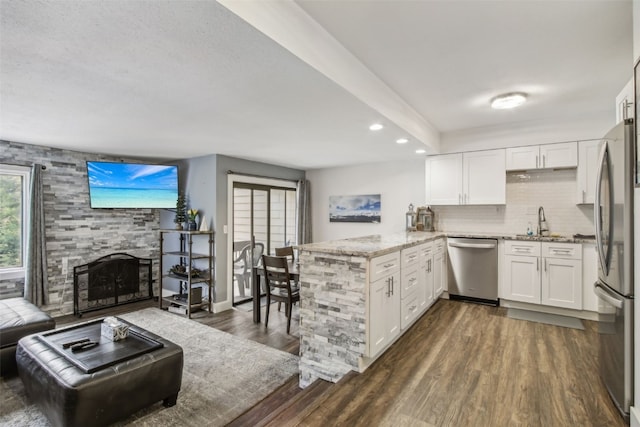kitchen featuring recessed lighting, white cabinets, a fireplace, a peninsula, and appliances with stainless steel finishes