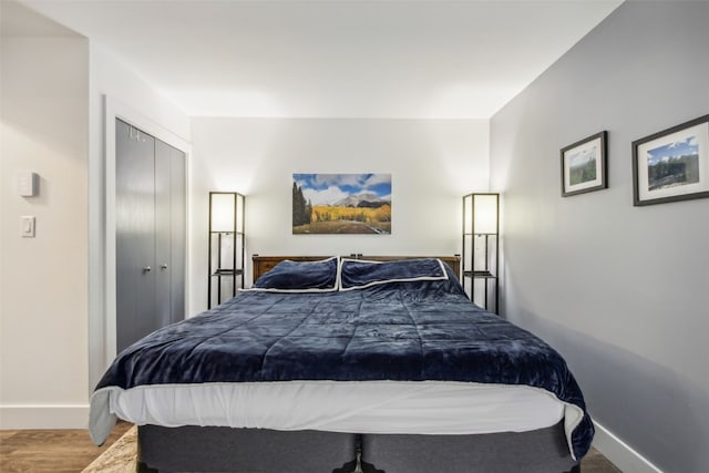bedroom with wood finished floors, a closet, and baseboards