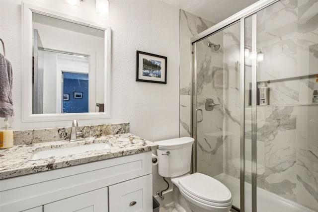 bathroom with toilet, vanity, and a marble finish shower