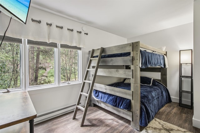 bedroom featuring a baseboard heating unit, wood finished floors, and baseboards