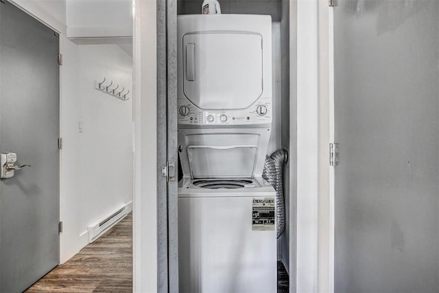 clothes washing area with wood finished floors, a baseboard heating unit, stacked washing maching and dryer, laundry area, and visible vents