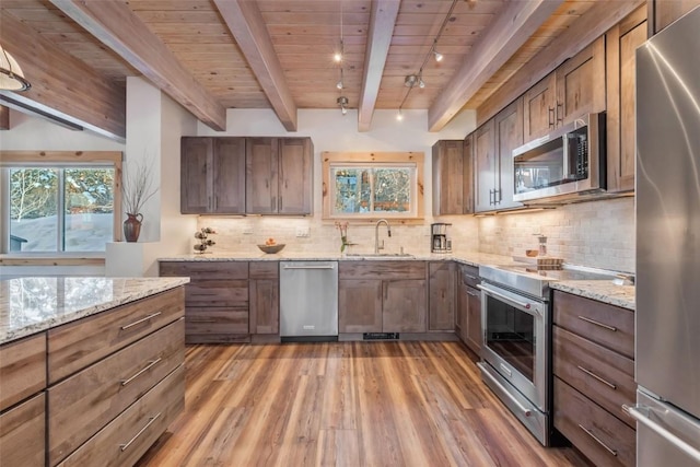2650 Medicine Springs Dr Unit 11, Steamboat Springs, CO 80487 - kitchen featuring appliances with stainless steel finishes, a sink, light wood-type flooring, wooden ceiling with exposed beams, and light stone counters