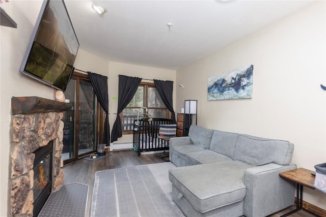 22714 US Highway 6 Unit 5958, Keystone, CO 80435 - living area featuring a stone fireplace, wood finished floors, a baseboard heating unit, and baseboards
