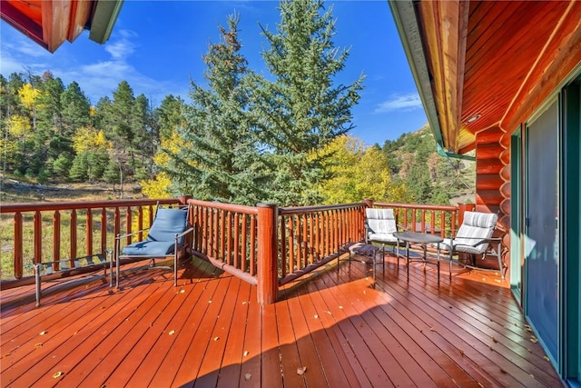 wooden terrace featuring a wooded view
