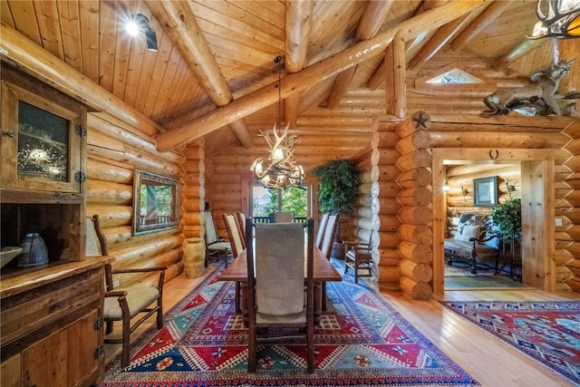 dining area featuring an inviting chandelier, log walls, and wood finished floors