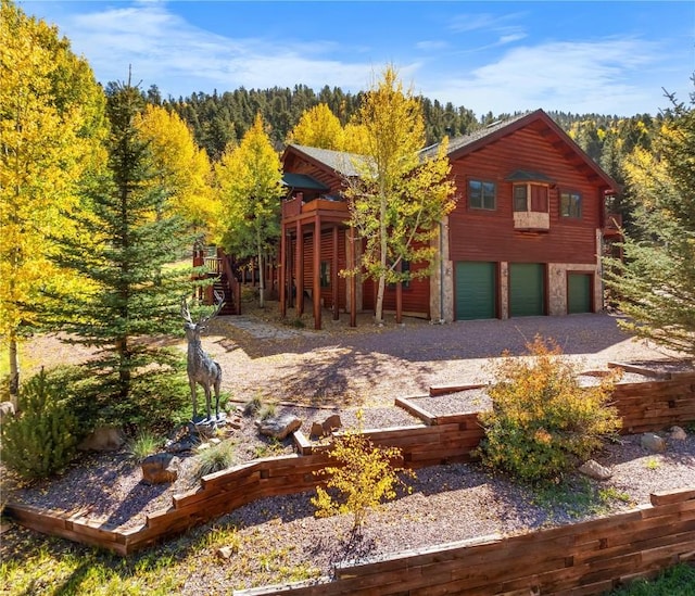 view of front of property featuring an attached garage, driveway, and a view of trees