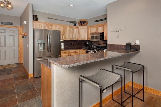 164 Buck Ridge Rd Unit 164, Summit Cove, CO 80435 - kitchen featuring stainless steel appliances, light brown cabinetry, decorative backsplash, a kitchen breakfast bar, and recessed lighting